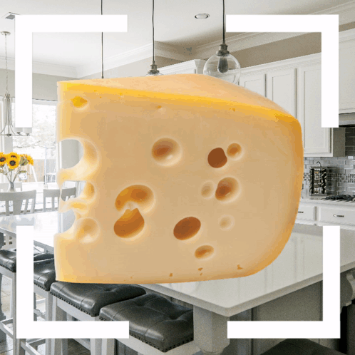 A Slice Of Cheese With Holes In It Is Hanging From The Ceiling In A Kitchen GIF
