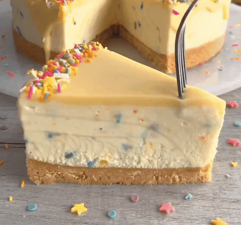 A Slice Of Cheesecake With Sprinkles On Top And A Fork Sticking Out Of It GIF