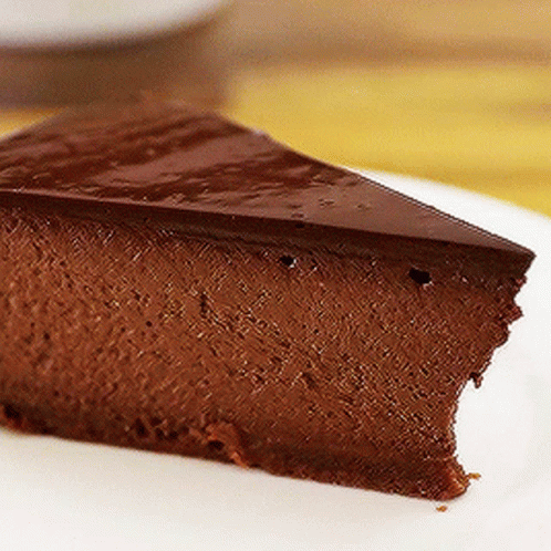 A Slice Of Chocolate Cheesecake Is On A White Plate GIF
