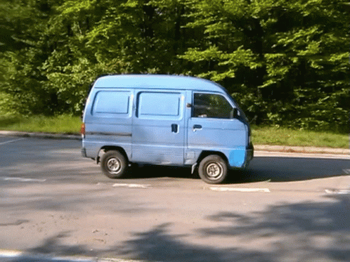 A Small Blue Van Is Parked In A Parking Lot GIF