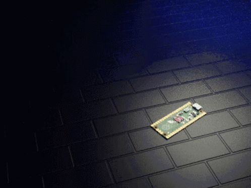 A Small Electronic Device Is Laying On A Black Tiled Floor GIF