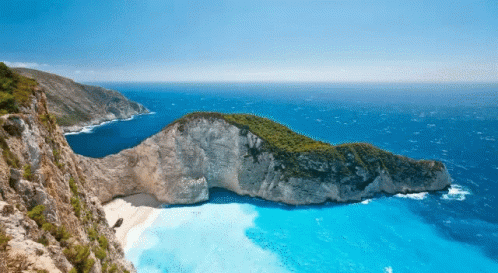 A Small Island In The Middle Of The Ocean With A Boat In The Water GIF