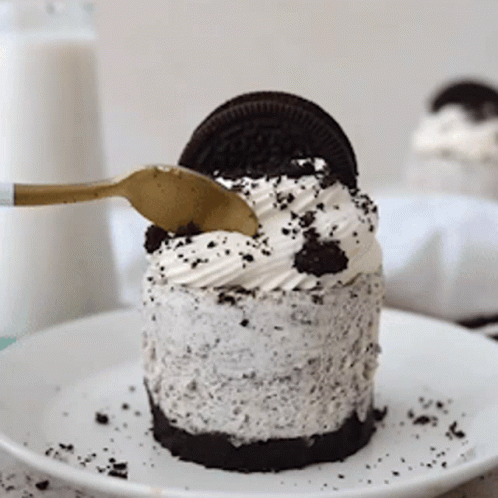 A Small Oreo Cheesecake On A White Plate With A Gold Spoon GIF
