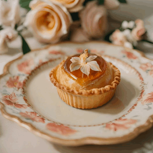 A Small Pastry With A Flower On Top Is On A Floral Plate GIF
