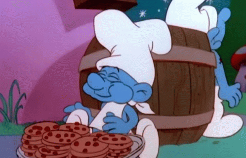 A Smurf In A Chef 'S Hat Is Holding A Bowl Of Chocolate Chip Cookies . GIF