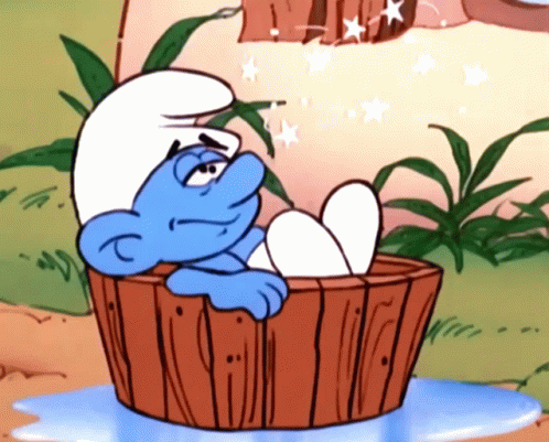 A Smurf Is Sitting In A Wooden Tub With His Feet In The Water GIF