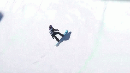 A Snowboarder Is Doing A Trick In Front Of A Fence That Says Stanley On It GIF