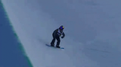 A Snowboarder Is Doing A Trick In The Air While Riding Down A Snowy Hill . GIF