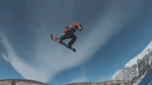 A Snowboarder Is Doing A Trick In The Air While Wearing A Red And White Jacket GIF