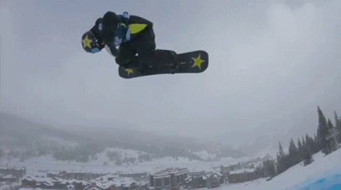 A Snowboarder Is Doing A Trick In The Air With A Star On His Board GIF