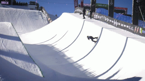 A Snowboarder Is Doing A Trick On A Snowy Ramp With A Breck Banner In The Background GIF
