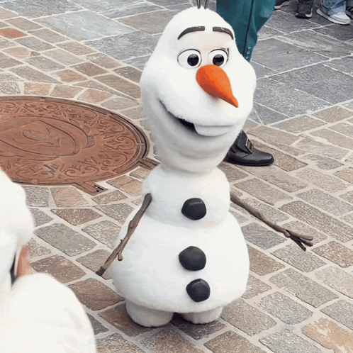 a snowman is standing on a brick sidewalk and smiling