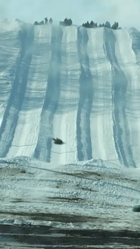 A Snowmobile Going Down A Snowy Hill GIF