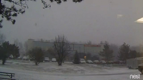 A Snowy Parking Lot In Front Of A Building With The Word Nest On The Bottom GIF