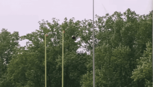 A Soccer Ball Is Flying Through The Air In Front Of A Forest GIF