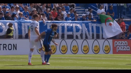 a soccer game is being played in front of a banner that says pizza pizza