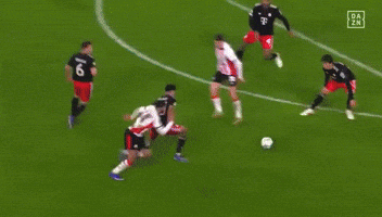 a soccer goalie is diving to catch the ball in front of a heineken ad