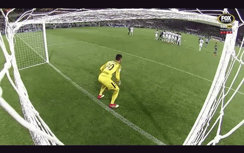 A Soccer Goalie Stands On The Edge Of The Goal Watching A Soccer Game Being Played . GIF