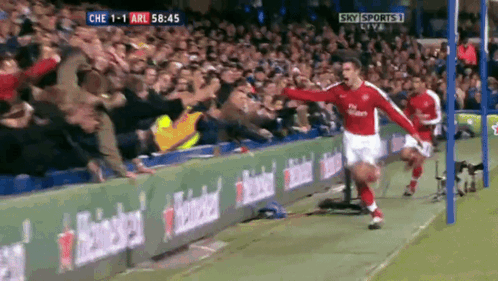 a soccer player celebrates a goal in front of a crowd with sky sports live in the background