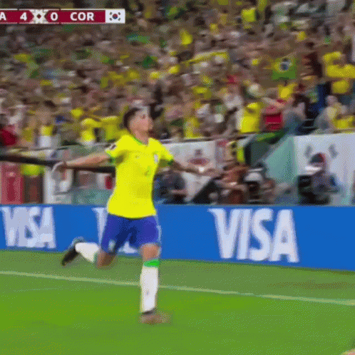 a soccer player celebrates a goal in front of a visa ad