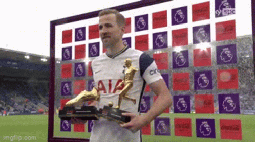 a soccer player holding a trophy in front of a sign that says aia