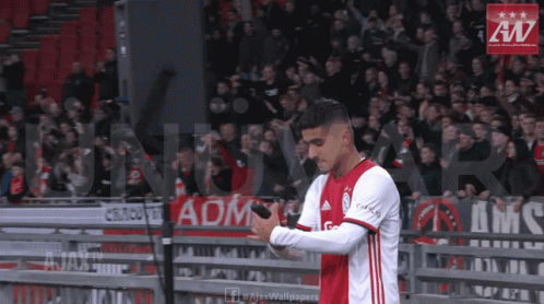 A Soccer Player Holds A Microphone In Front Of A Banner That Says Ajax Wallpaper GIF