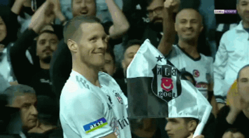 a soccer player holds up a flag with a shield on it