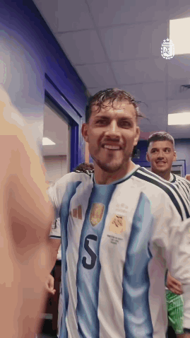 a soccer player in a blue and white jersey with the number 5 on it is smiling in a locker room .