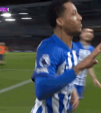 A Soccer Player In A Blue And White Uniform Is Celebrating A Goal On A Field . GIF