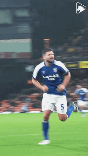 a soccer player in a blue and white uniform is running on a field .