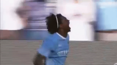 A Soccer Player In A Blue Jersey Is Jumping In The Air While Wearing Headphones . GIF