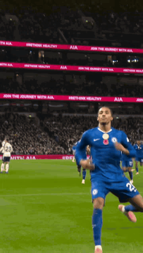 A Soccer Player In A Blue Jersey Is Running On A Field With A Sign That Says Join The Journey With Aia GIF