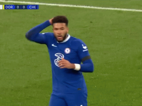 A Soccer Player In A Blue Jersey Is Standing On A Soccer Field With His Hand On His Head . GIF