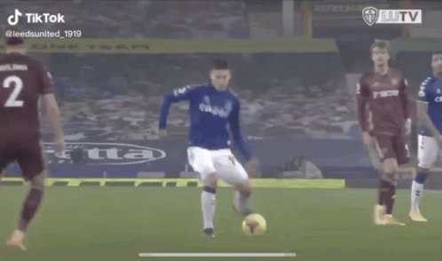 A Soccer Player In A Blue Uniform Is Running Towards The Ball . GIF