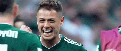 a soccer player in a green jersey is laughing and celebrating a goal with his teammates .