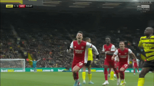 a soccer player in a red emirates fly better jersey celebrates