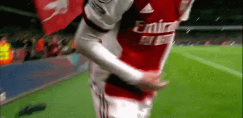 a soccer player in a red emirates jersey is hugging another player on the field .