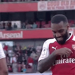 A Soccer Player In A Red Emirates Jersey Is Standing On A Field . GIF