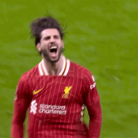 A Soccer Player In A Red Jersey Is Kicking A Ball On A Soccer Field . GIF