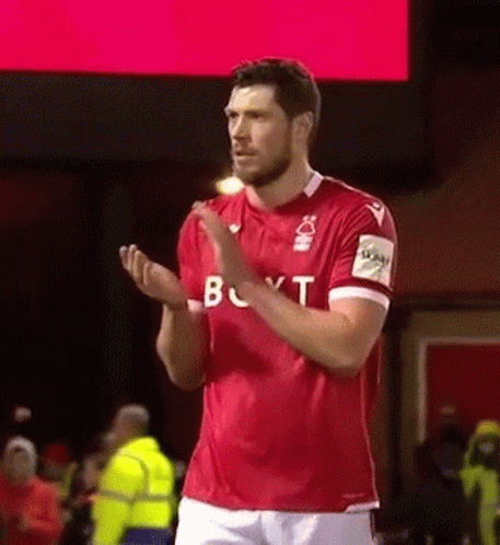 A Soccer Player In A Red Shirt Is Applauding The Crowd . GIF