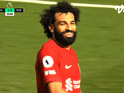 A Soccer Player In A Red Shirt Is Looking Down At Something GIF