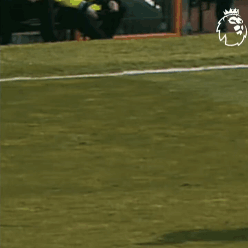 A Soccer Player In A Red Shirt Is Running Towards Another Player In A Black And White Striped Shirt On A Field . GIF