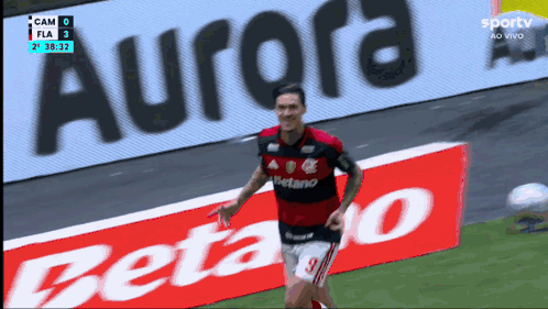a soccer player in front of an ad for aurora