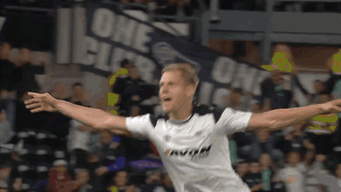 A Soccer Player Is Celebrating A Goal In Front Of A Banner That Says One GIF