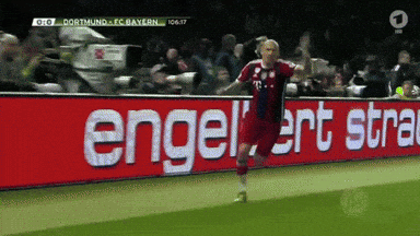 a soccer player is celebrating a goal in front of a sign that says engelert stra
