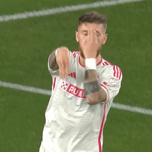 A Soccer Player Is Covering His Face With His Hands While Wearing A White Jersey With Red Stripes GIF