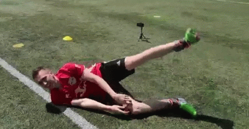 A Soccer Player Is Doing A Trick On The Field While Laying On The Ground . GIF