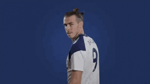 A Soccer Player Is Flexing His Muscles While Wearing A White Jersey With A Number 9 On It . GIF