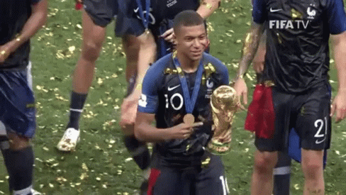 A Soccer Player Is Holding A Trophy And A Medal While His Teammates Celebrate . GIF