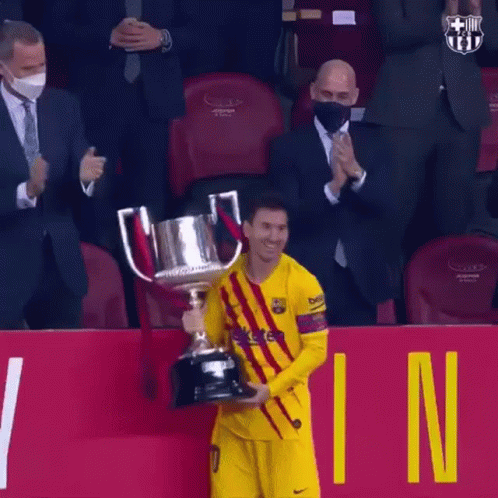 A Soccer Player Is Holding A Trophy In Front Of A Crowd While Wearing A Mask . GIF